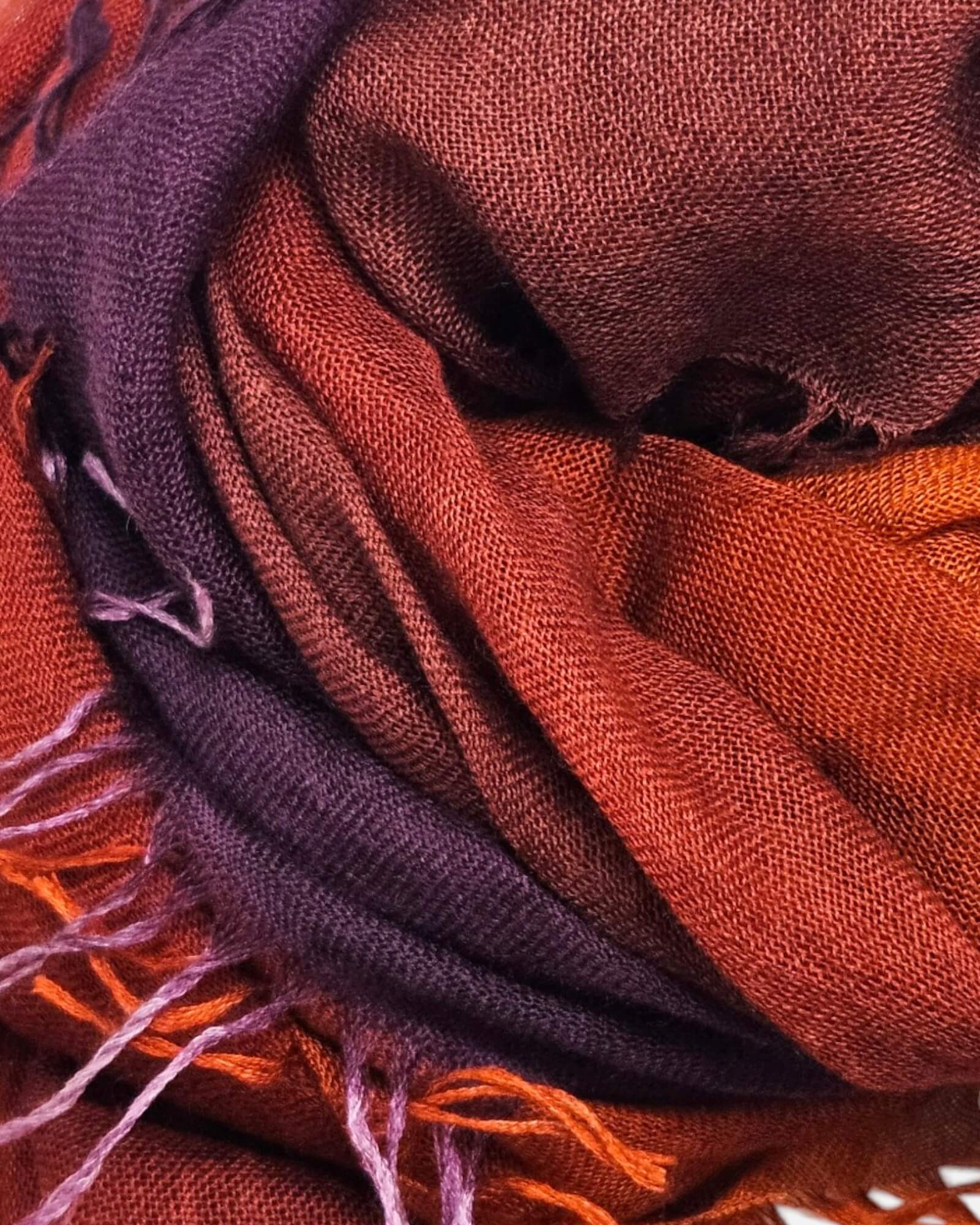 Primer plano en detalle de los pliegues y la textura afelpada en cashmere y seda del foulard Faliero Sarti Enrichetta en tonos berenjena y teja.