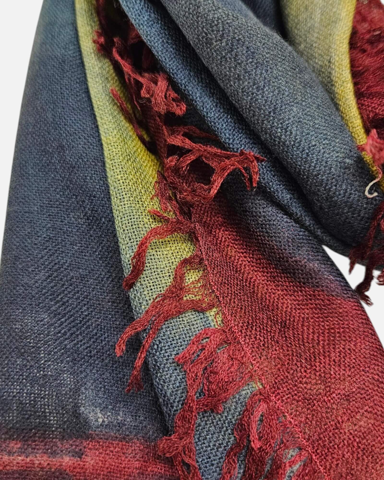 Primer plano en detalle de los flecos granate y la textura suave de lana y seda del foulard Faliero Sarti Ella.