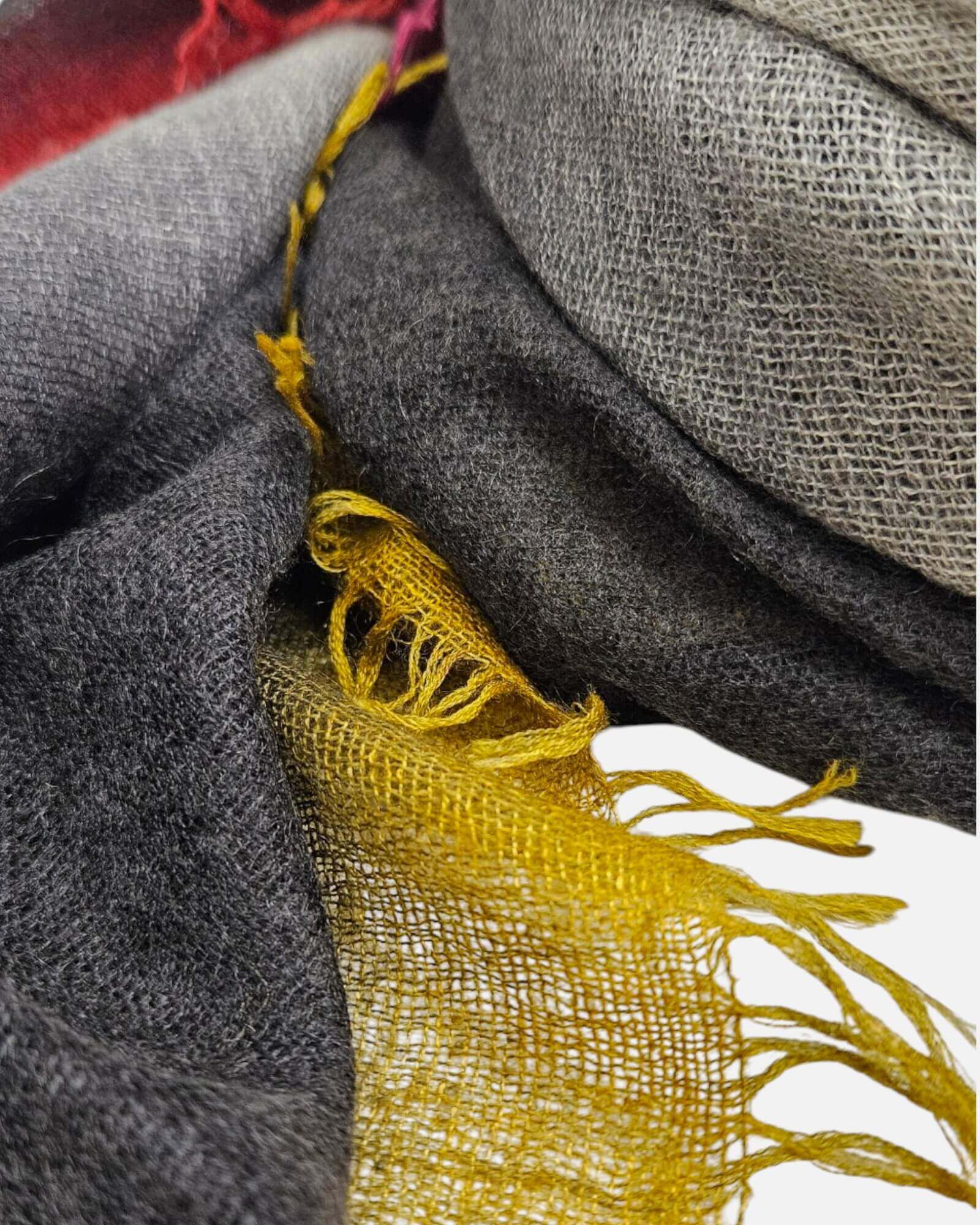 Primer plano en detalle de la textura esponjosa de seda y cashmere del pañuelo Faliero Sarti Kamala mostrando los flecos artesanales en tono mostaza.