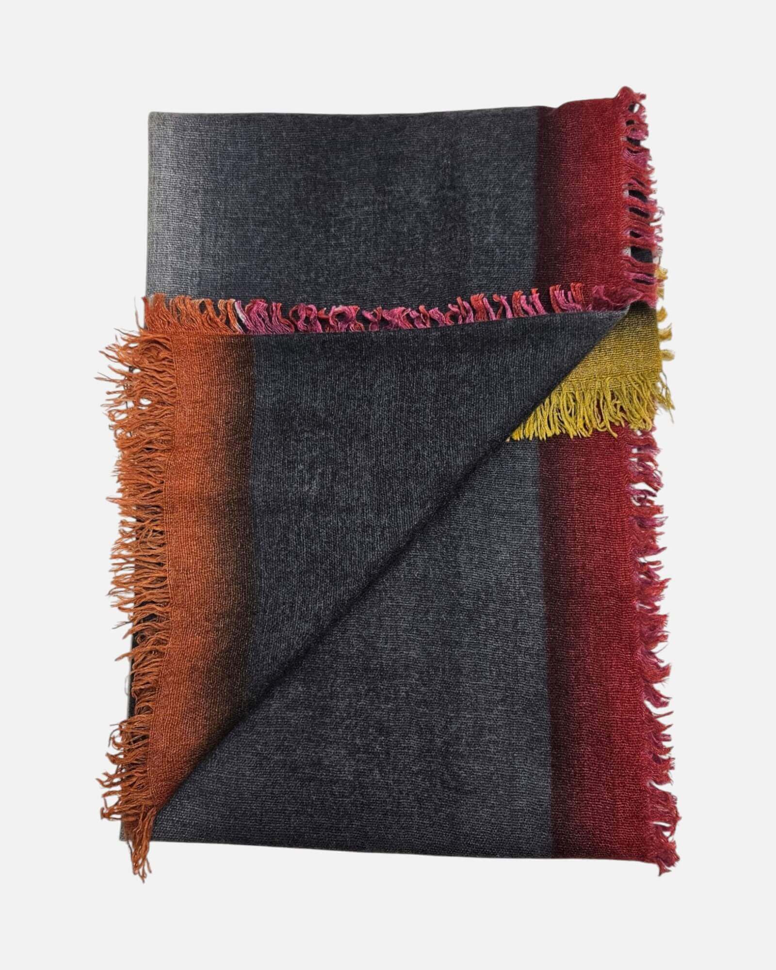 Vista doblada del foulard Faliero Sarti Kamala mostrando la combinación de bloques de color gris antracita, teja y borgoña con sus bordes de flecos.