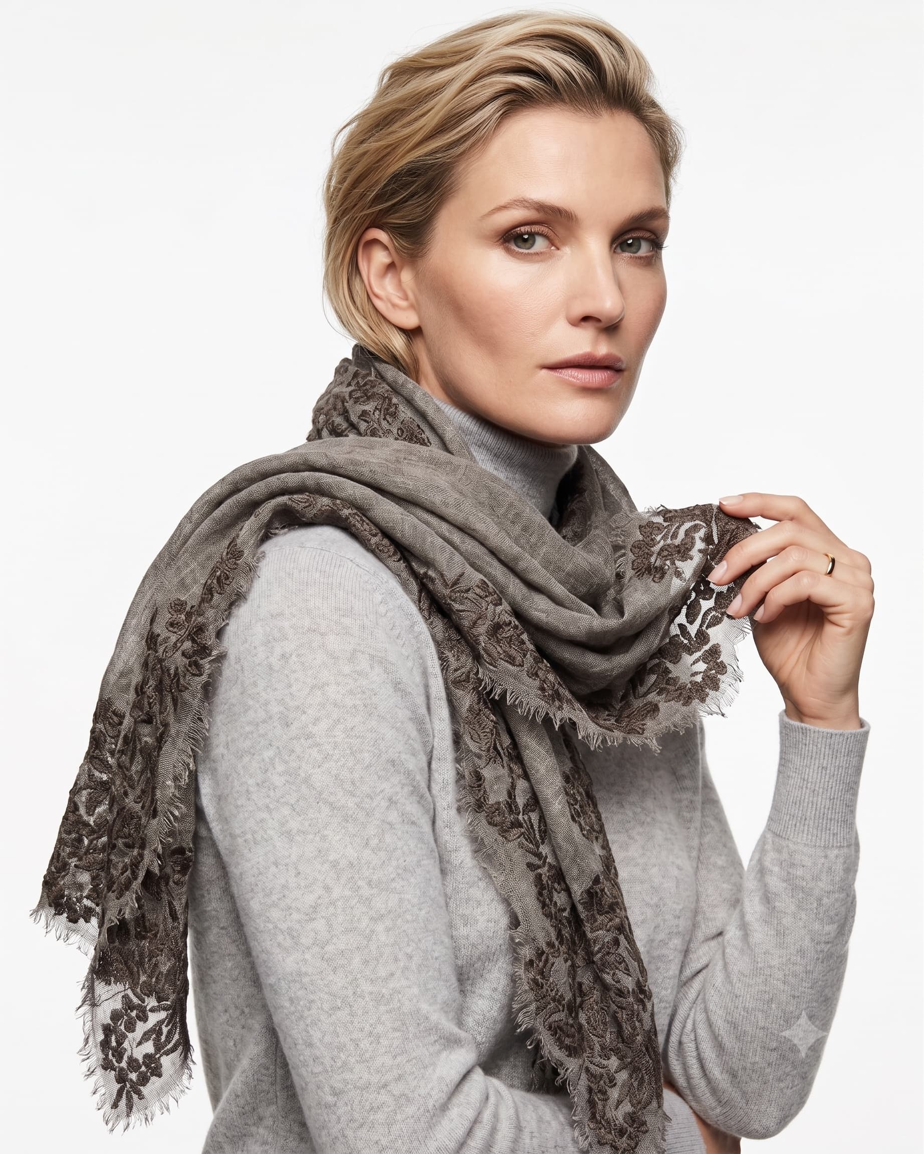 Modelo luciendo el foulard Faliero Sarti Fiorenza en lana gris con bordes de encaje bordado sobre jersey claro.