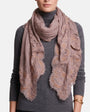 Modelo luciendo la estola de lana y encaje Faliero Sarti Fiorenza en tono rosa empolvado y dorado sobre un jersey gris de cuello alto.