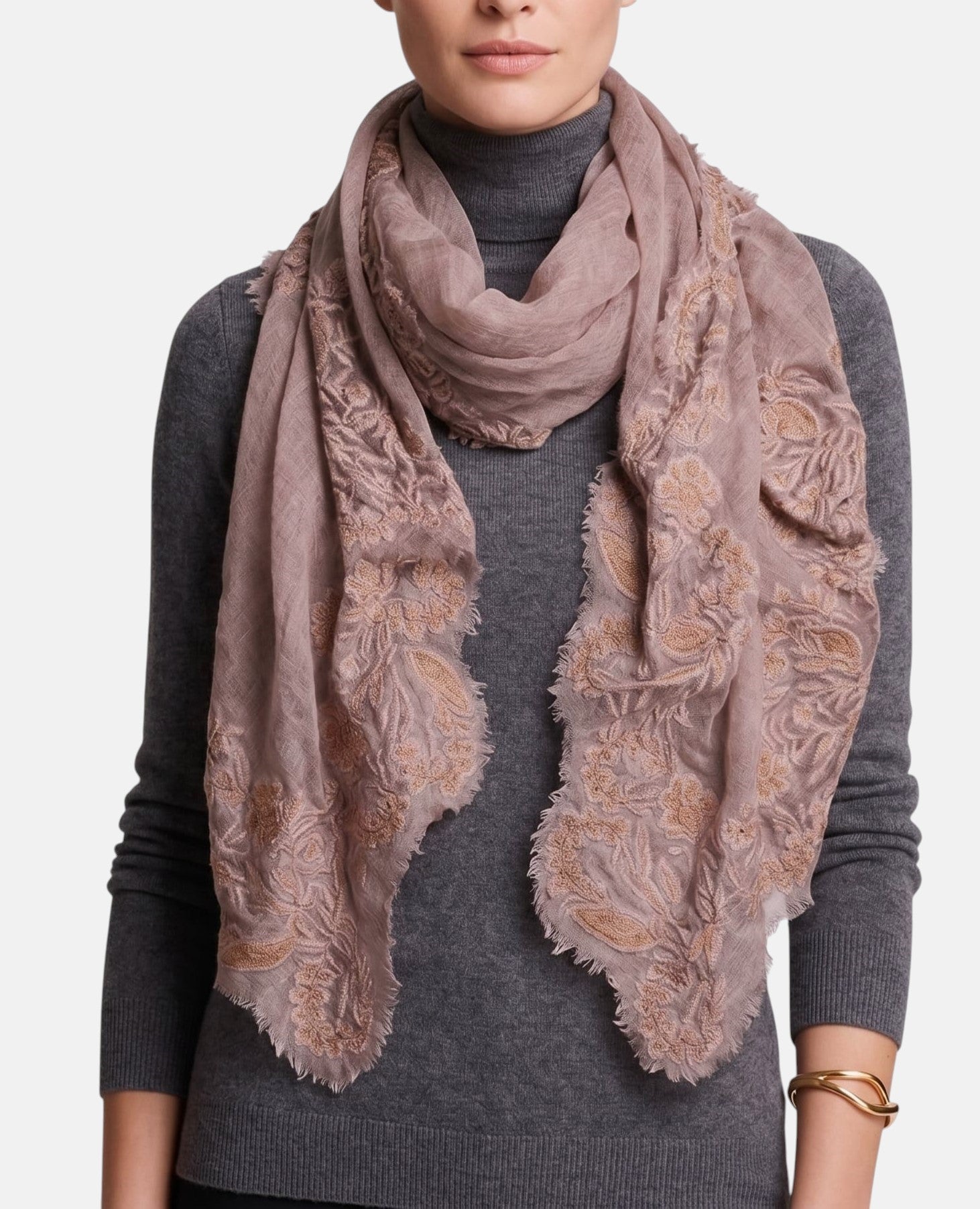 Modelo luciendo la estola de lana y encaje Faliero Sarti Fiorenza en tono rosa empolvado y dorado sobre un jersey gris de cuello alto.