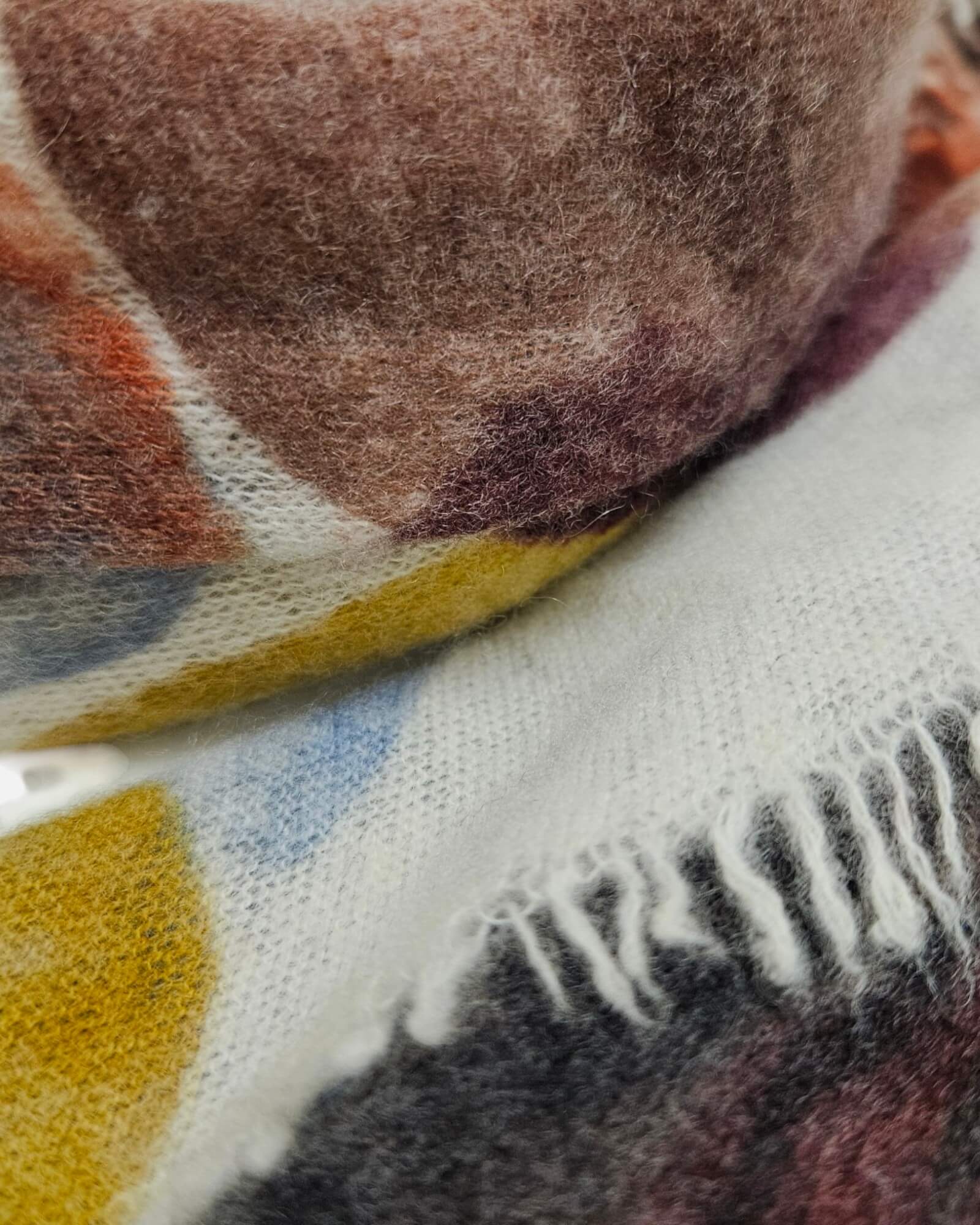 Primer plano de la textura ultrasuave del cashmere y el remate de flecos del pañuelo Faliero Sarti.