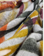 Primer plano del tejido esponjoso de cashmere del foulard Faliero Sarti Melany mostrando las llanas de cuadros en teja y mostaza.