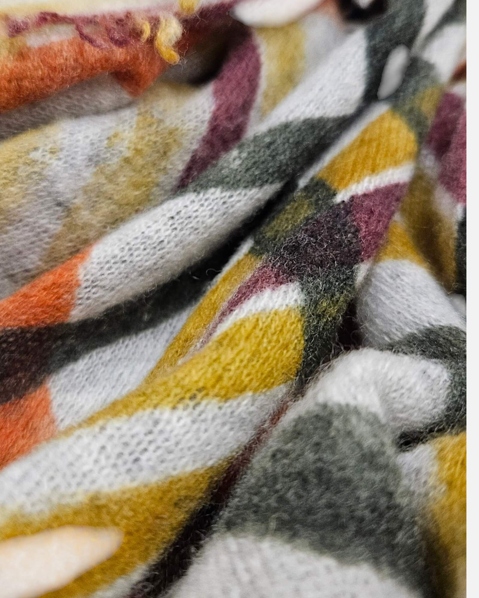 Primer plano del tejido esponjoso de cashmere del foulard Faliero Sarti Melany mostrando las llanas de cuadros en teja y mostaza.