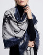 Modelo luciendo el foulard de cashmere Faliero Sarti Pia drapeado sobre los hombros con fondo azul marino y gris sobre un jersey negro.