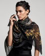 Modelo luciendo el pañuelo Faliero Sarti Elisabetta cruzado al cuello con estampado floral dorado y trazos blancos sobre vestido negro.