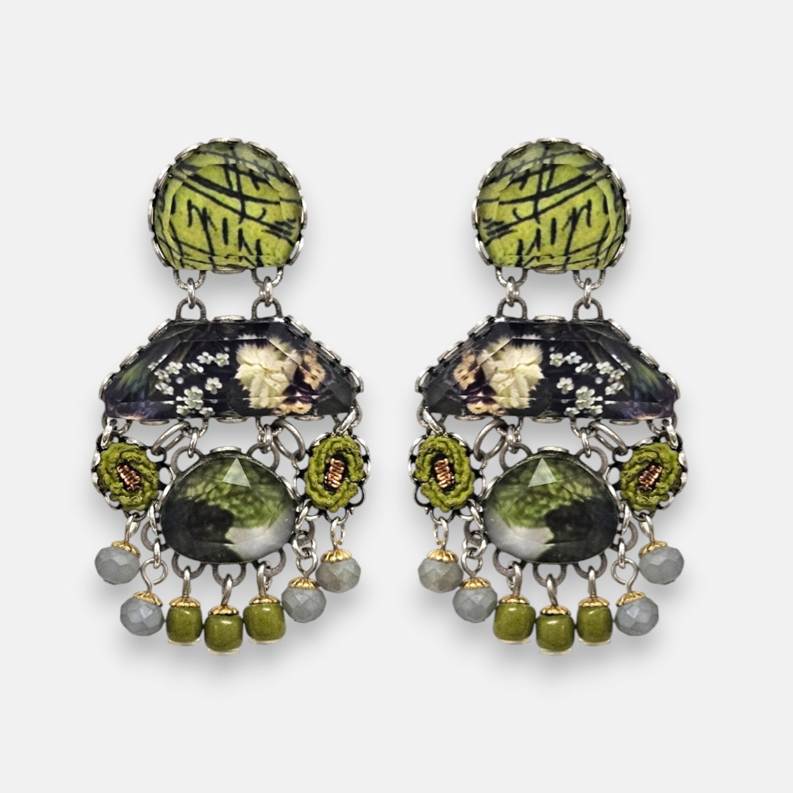 pendientes expuesto de frente sobre un fondo gris claro, detallando su silueta simétrica de estilo bohemio con cabujones verdes y grises.
