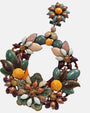 Detalle artesanal de flores esmaltadas, hojas metalizadas y base de carey en pendientes Dublos
