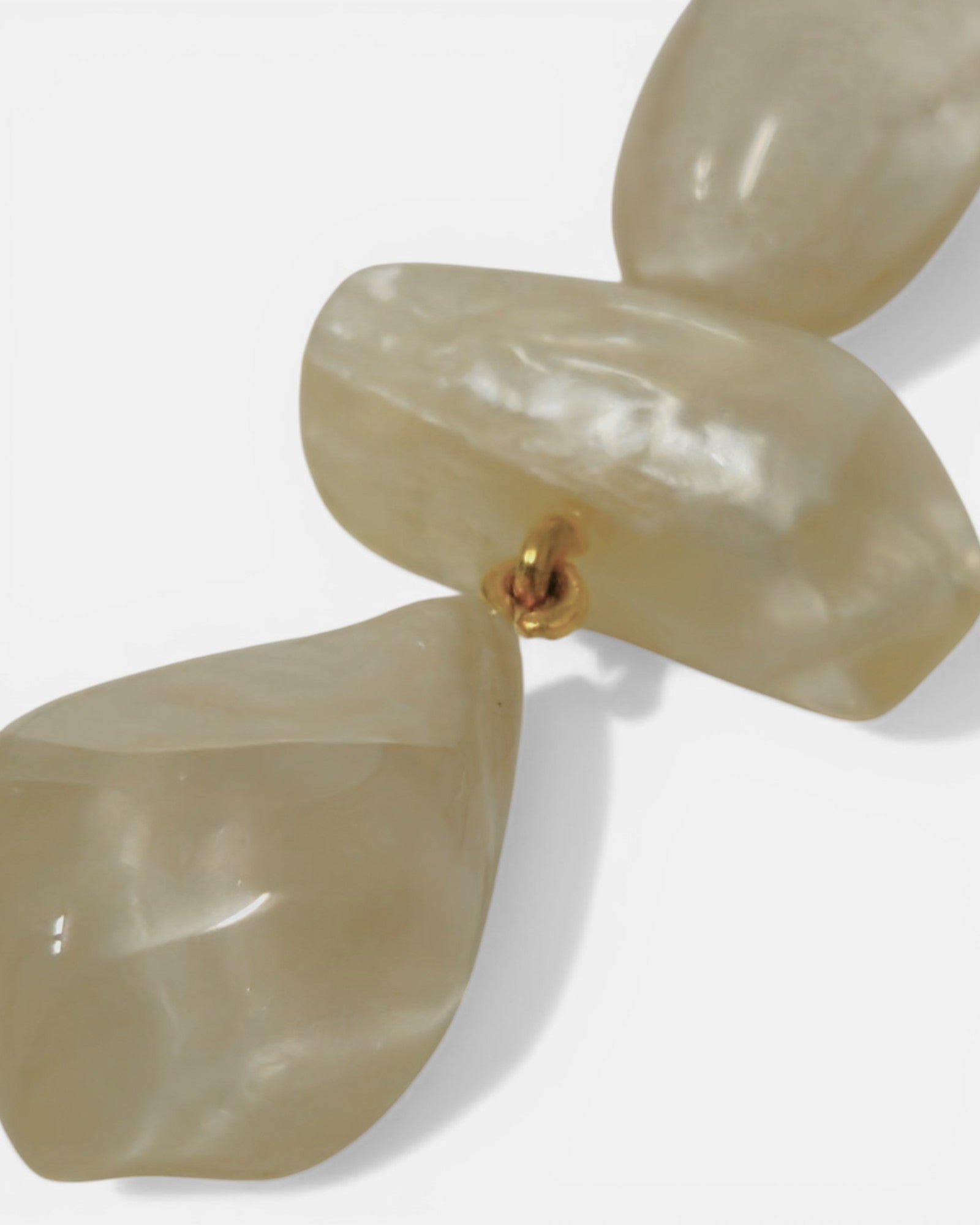 Detalle de la textura nacarada de la resina de Dominique Denaive unida por anilla dorada.