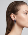 modelo de perfil luciendo uno de los pendientes colgantes, apreciando su caída sofisticada y su escala equilibrada con el rostro.