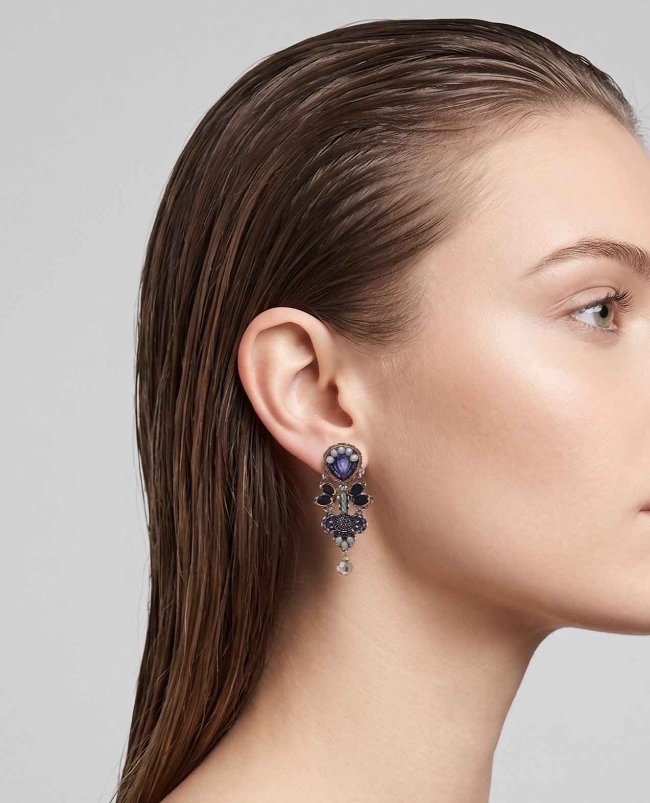 modelo de perfil luciendo uno de los pendientes colgantes, apreciando su caída sofisticada y su escala equilibrada con el rostro.