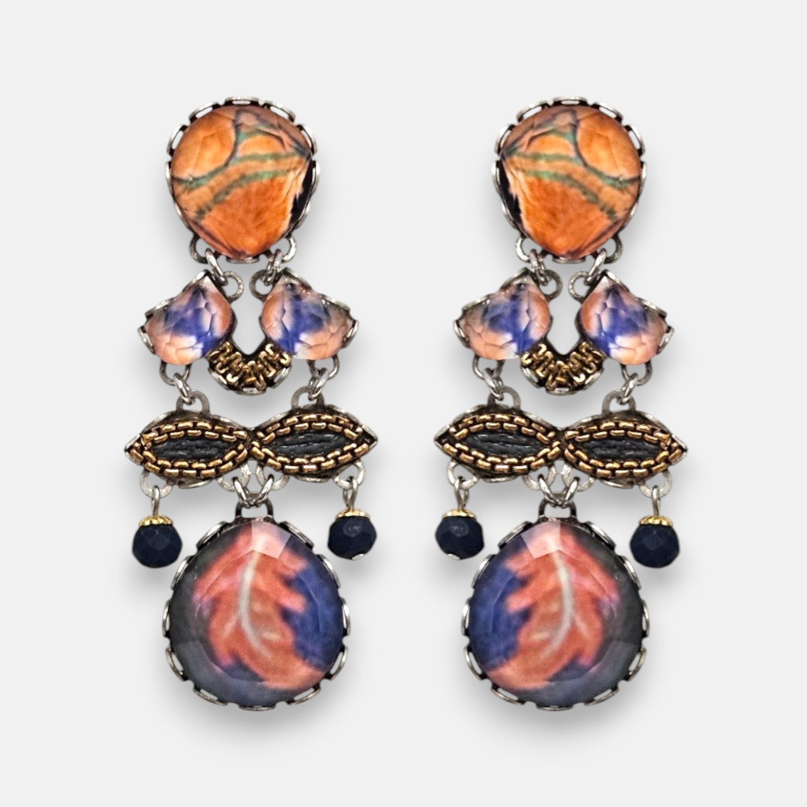 par de pendientes expuesto de frente sobre fondo neutro, detallando su composición simétrica con tonos terracota, malva y azul noche.