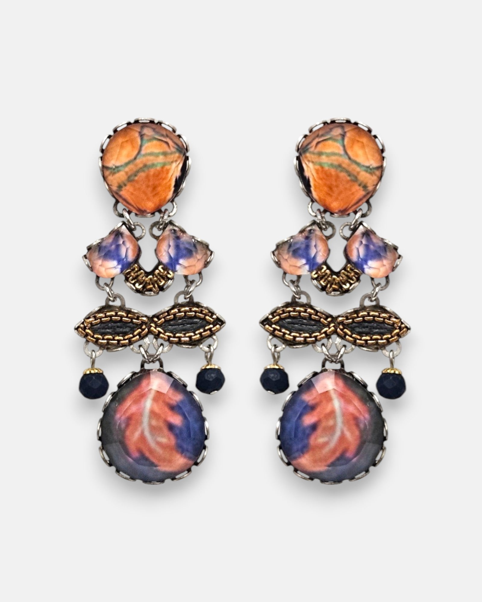 par de pendientes expuesto de frente sobre fondo neutro, detallando su composición simétrica con tonos terracota, malva y azul noche.