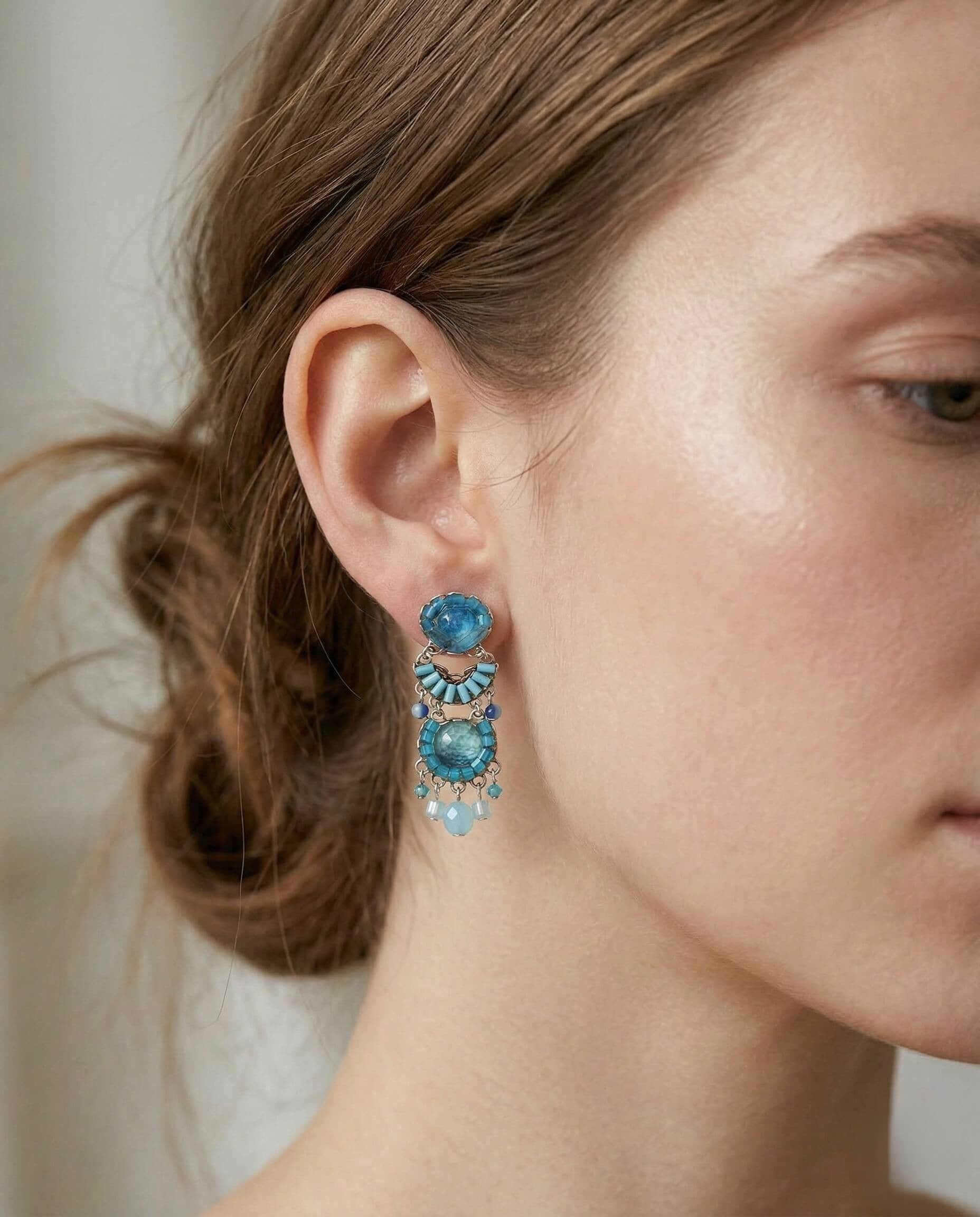 Mujer luciendo los pendientes Estival de Ayala Bar en tonos celestes con un peinado recogido.