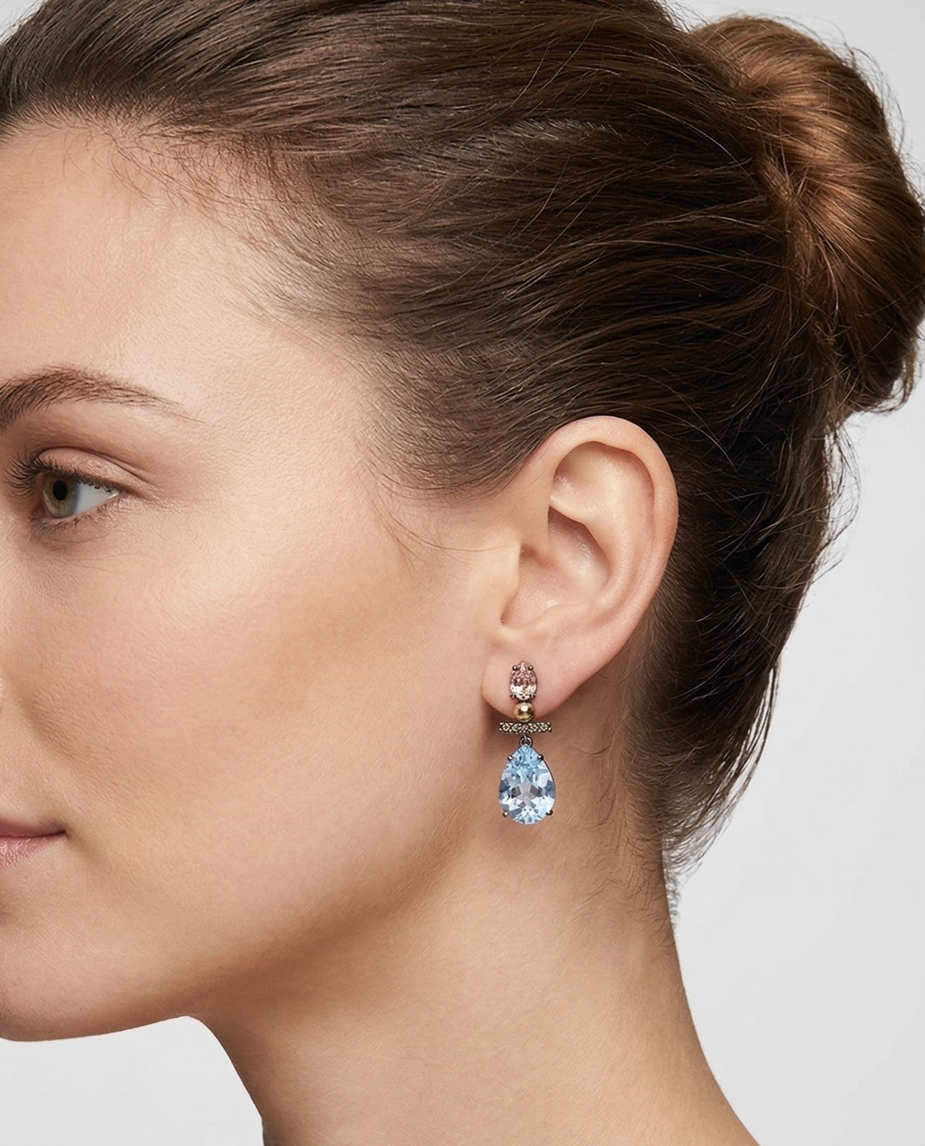 Mujer luciendo los pendientes articulados Azure Drop de Bohemme, resaltando su brillo azul y diseño estilizado.