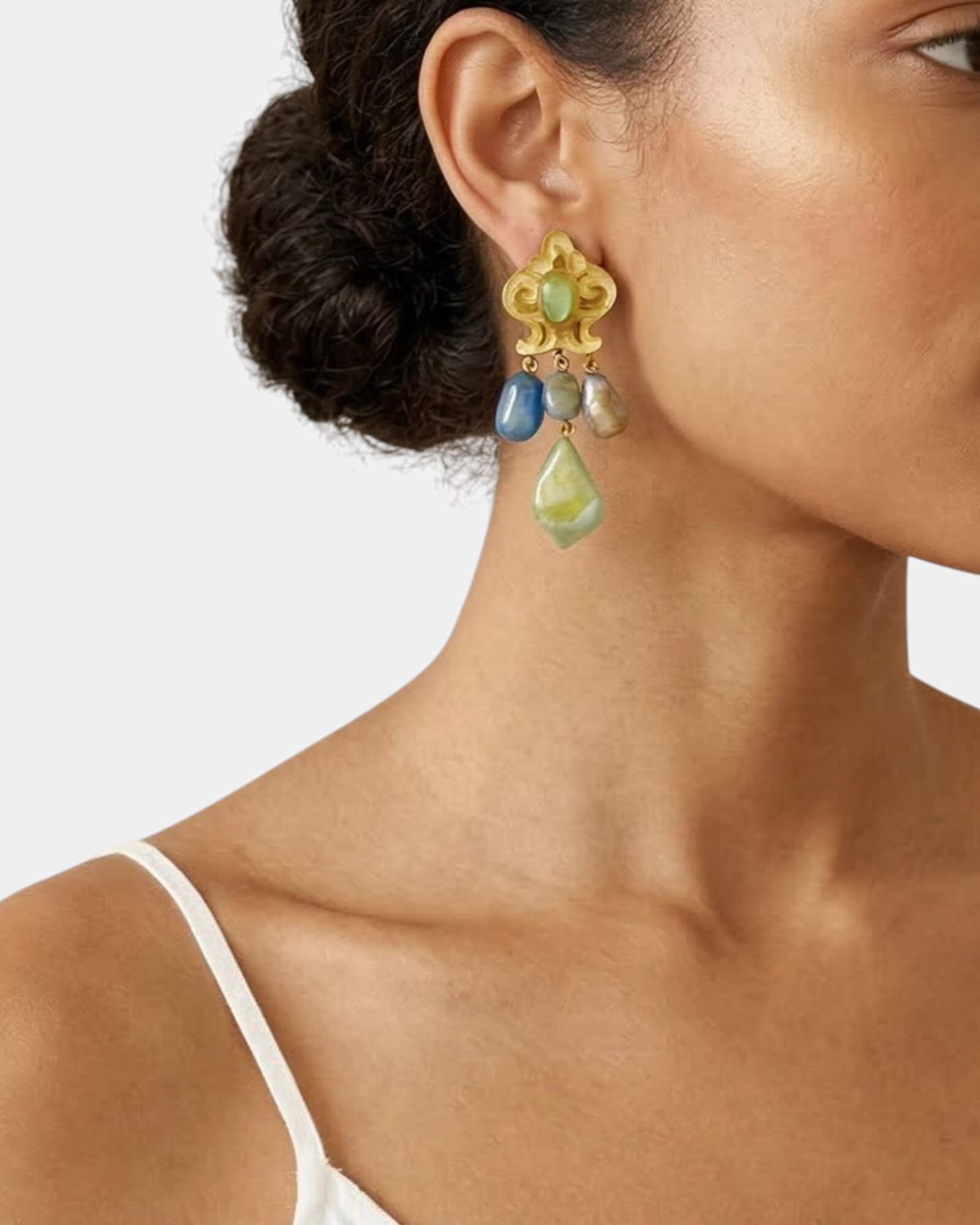 Mujer luciendo los pendientes Grizzy Multisky, mostrando su tamaño y cómo aportan luz al rostro con un look de seda gris.