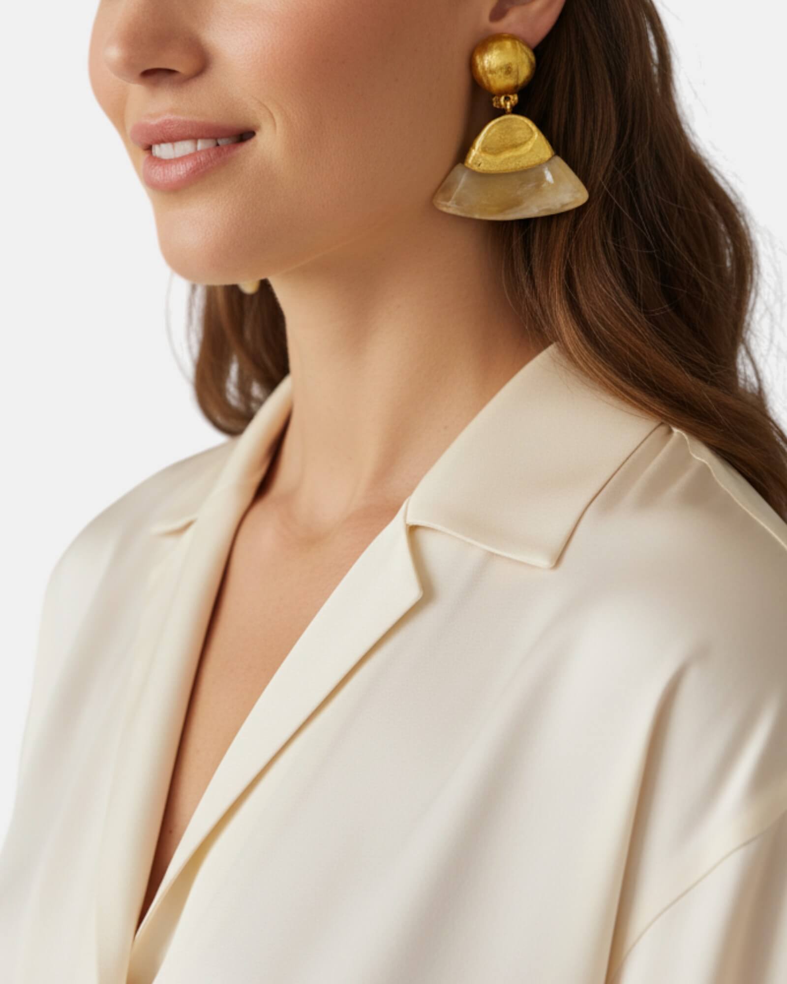 Mujer luciendo los pendientes Isma de clip de Dominique Denaive sobre un jersey de seda crema minimalista.