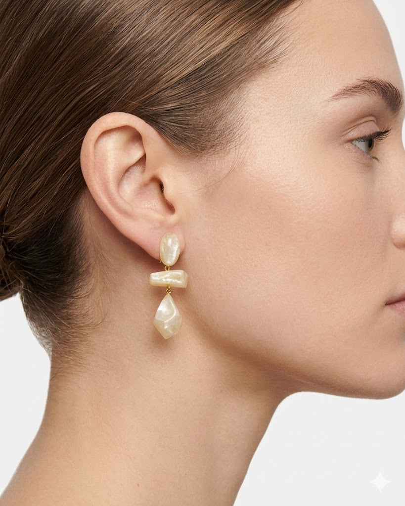 Mujer luciendo los pendientes Isma Dune de Dominique Denaive sobre un look en tonos crema, destacando su volumen y elegancia.