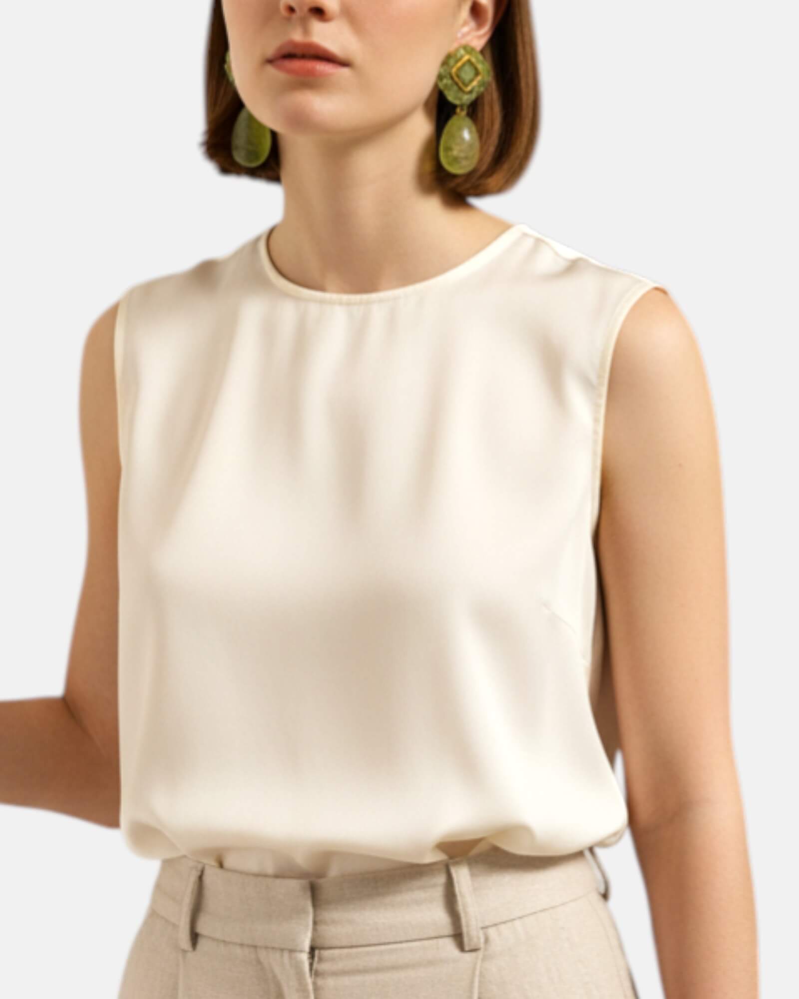 Mujer luciendo los pendientes Althea Verde de Dominique Denaive sobre un look en tonos crema, destacando su volumen y elegancia.