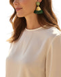 Mujer luciendo los pendientes Simone Matcha, mostrando su caída elegante y cómo resaltan sobre una blusa de seda clara.
