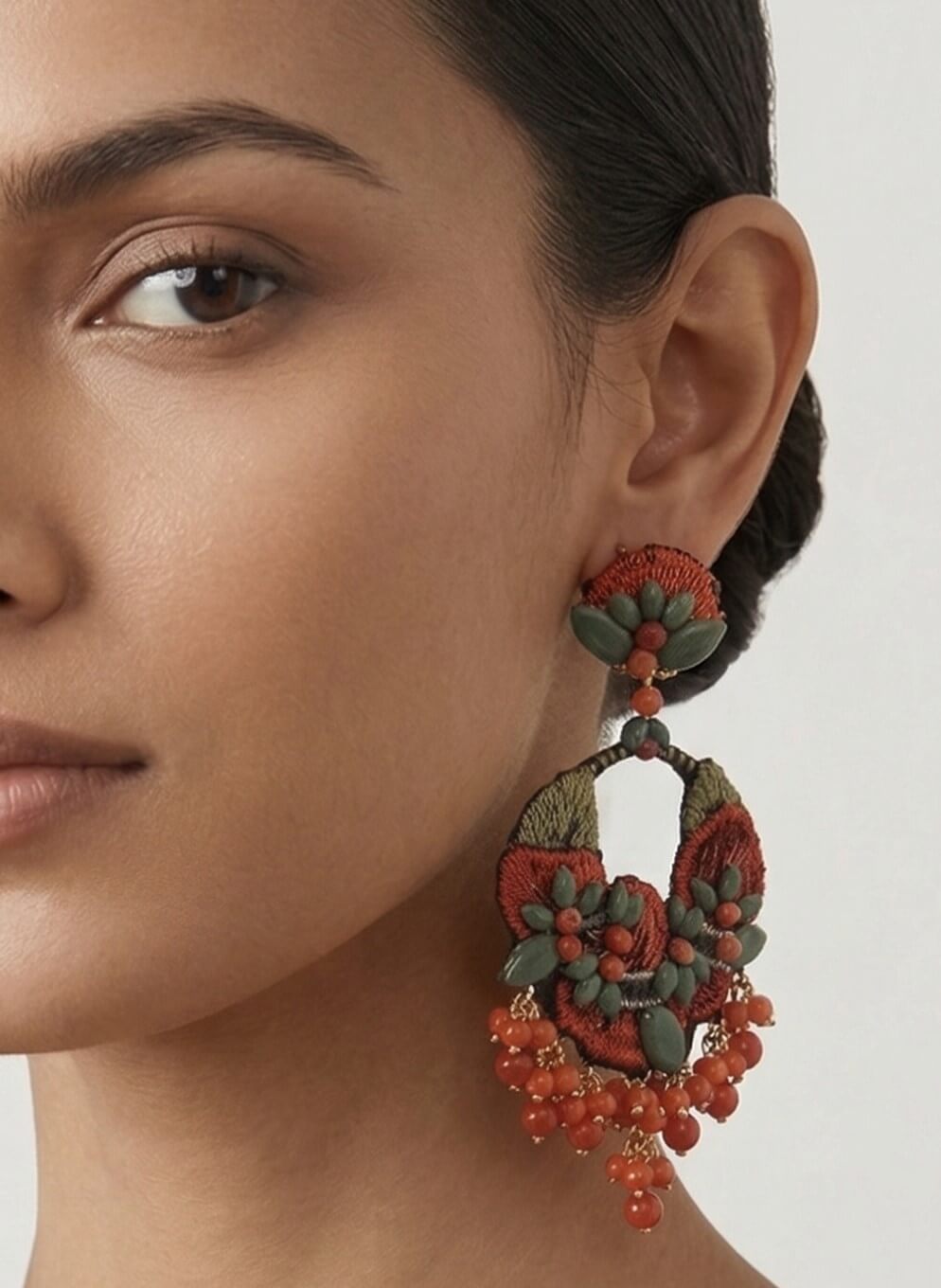 Mujer luciendo los pendientes maxi Dublos de bordado, destacando su tamaño statement y su colorido orgánico de fiesta.