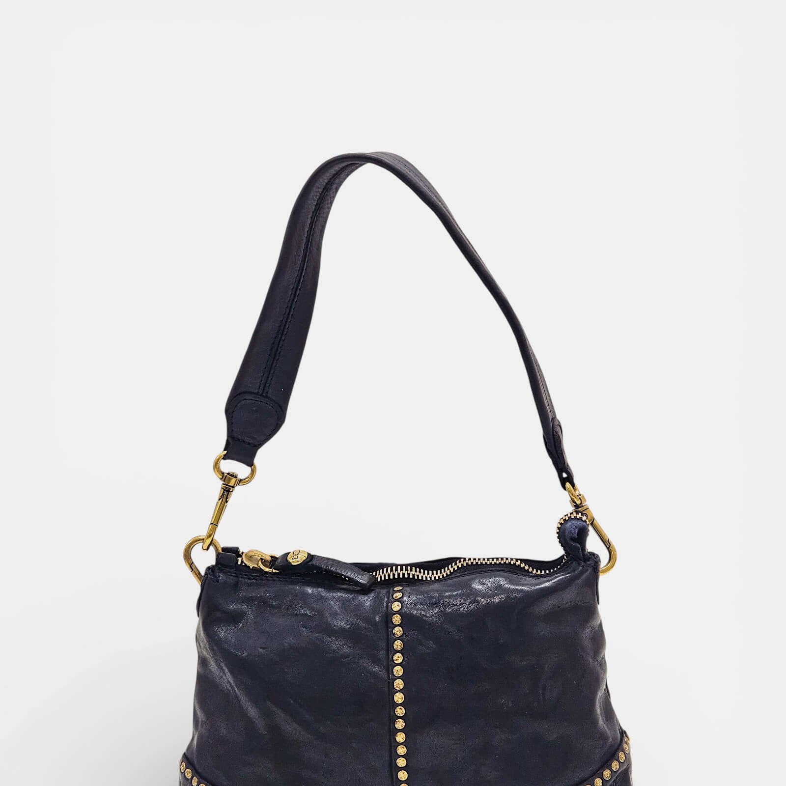 Vista frontal de bolso azul Campomaggi con línea vertical de tachuelas doradas.