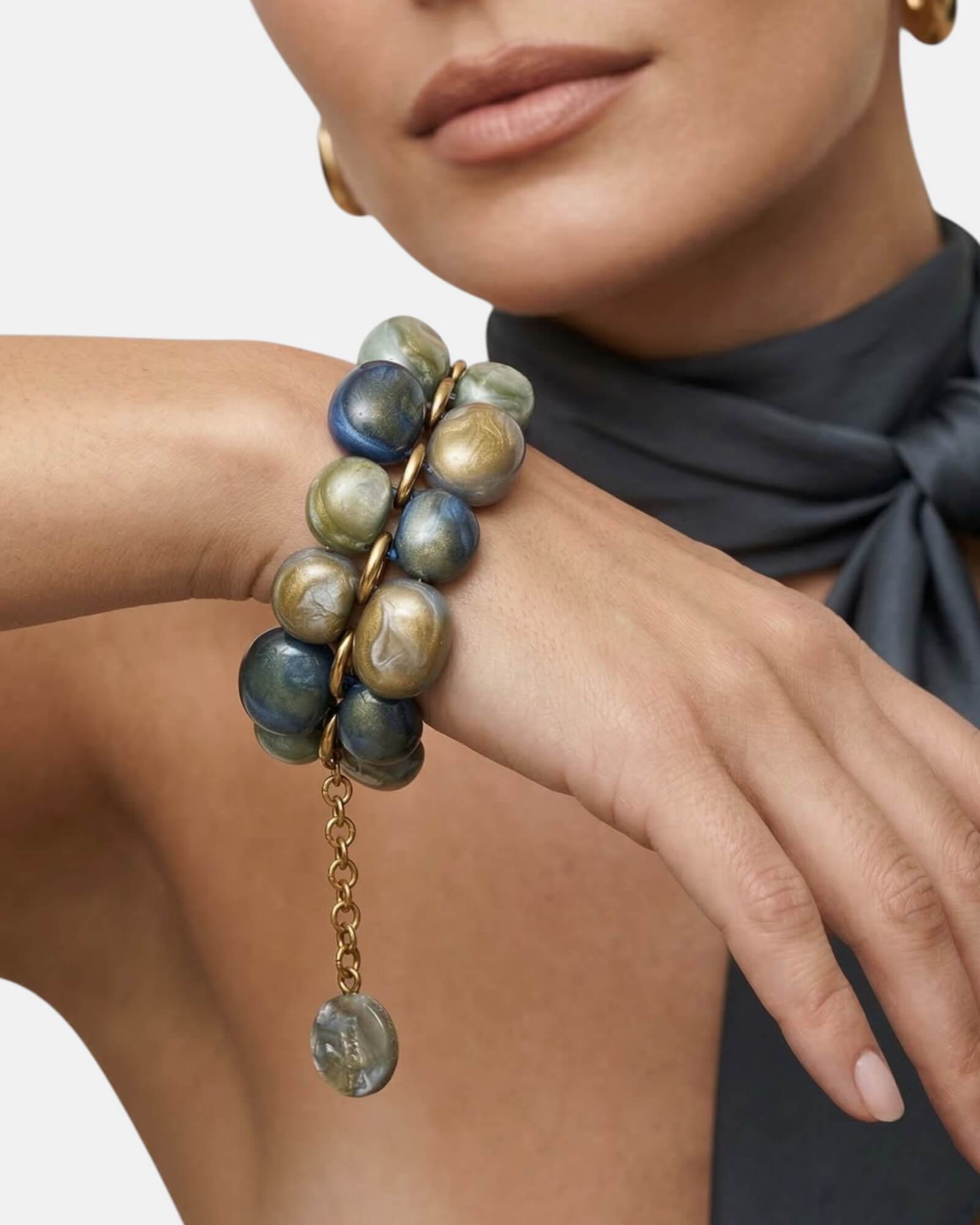 Mujer luciendo la pulsera Andrea Multisky con un sofisticado look de seda gris, destacando el volumen y brillo de la pieza.