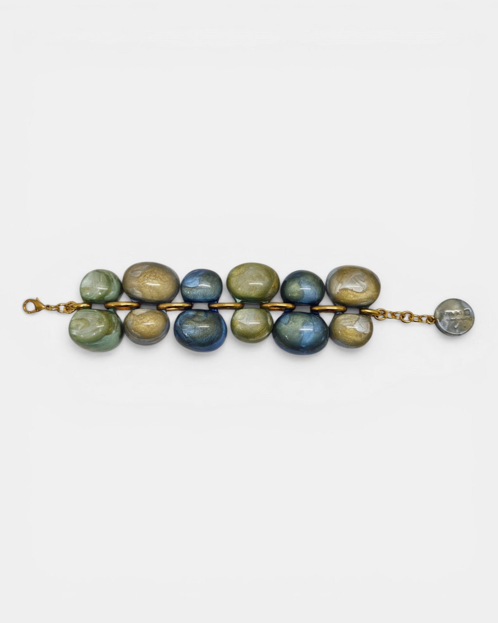 Pulsera Andrea de Dominique Denaive con dos hileras de cuentas de resina en tonos azul, verde y oro sobre fondo blanco.