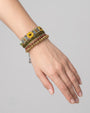 modelo luciendo la pulsera ancha articulada, permitiendo apreciar el relieve de sus texturas verdes y amarillas y cómo adorna la muñeca.