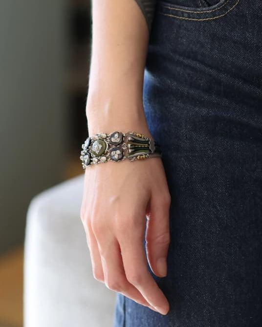 modelo luciendo el brazalete ancho articulado, apreciando el grosor del diseño, sus texturas orgánicas y la caída de la cadena metálica de seguridad.