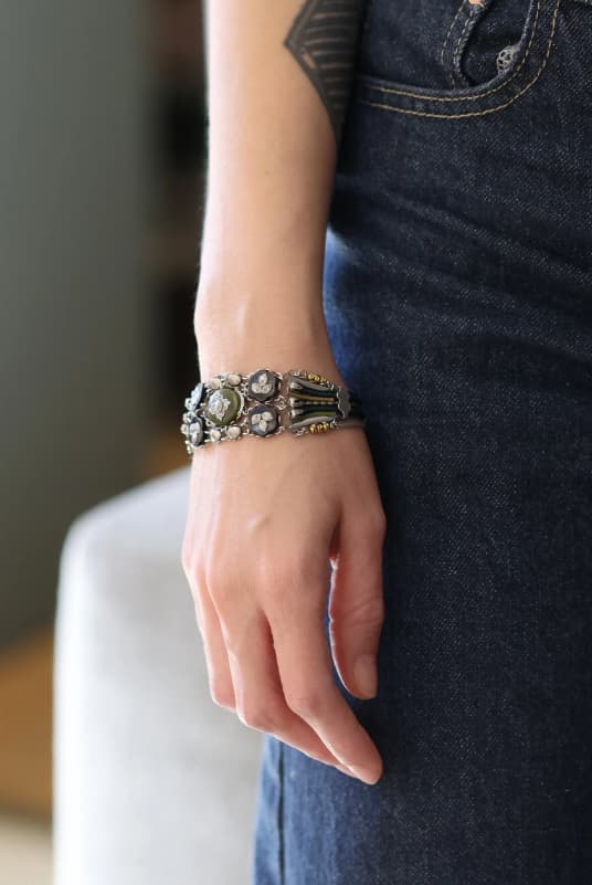 modelo luciendo el brazalete ancho articulado, apreciando el grosor del diseño, sus texturas orgánicas y la caída de la cadena metálica de seguridad.